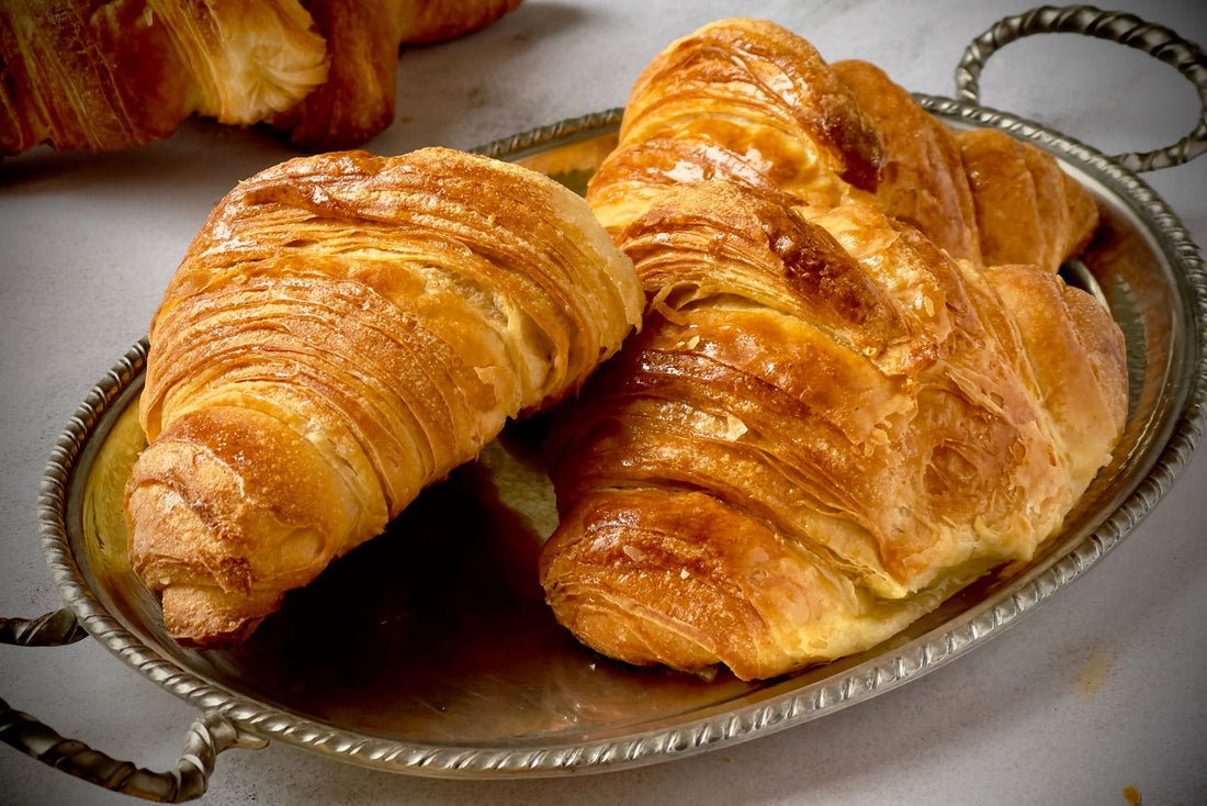 Vers gebakken botercroissants met krokante, goudbruine laagjes op een schaal