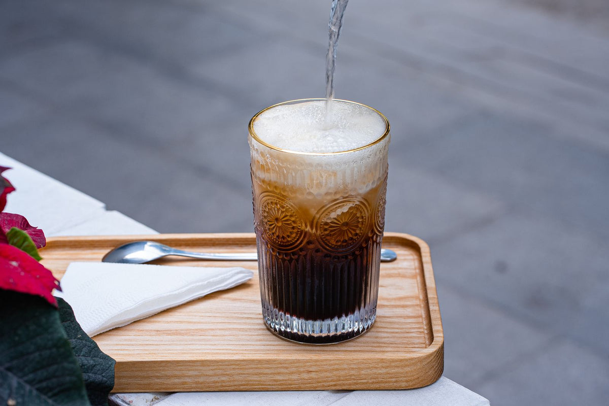 Bruisende tonic wordt over ijs en espresso in een hoog glas geschonken