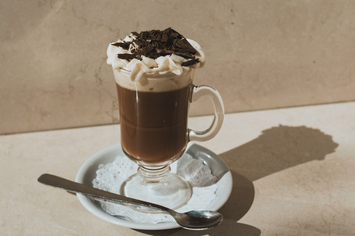 Bicerin in een glas op voet, met donkere koffie, een laag opgeklopte slagroom en geschaafde pure chocolade erbovenop