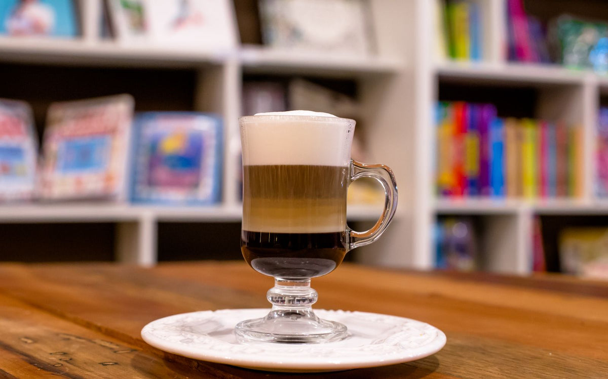 Glas koffie verkeerd met een laag warme melk en schuim op een houten tafel