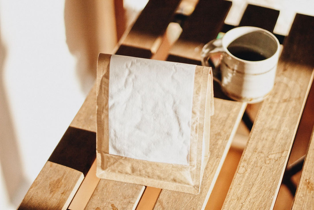 Zak koffiebonen van kraftpapier op een houten tafel, klaar om weg te geven
