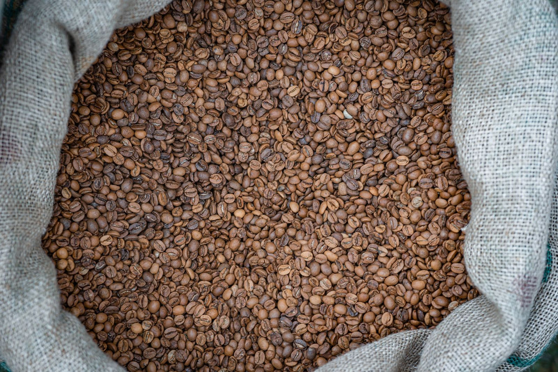 Jute zak gevuld met geroosterde koffiebonen, van bovenaf gefotografeerd