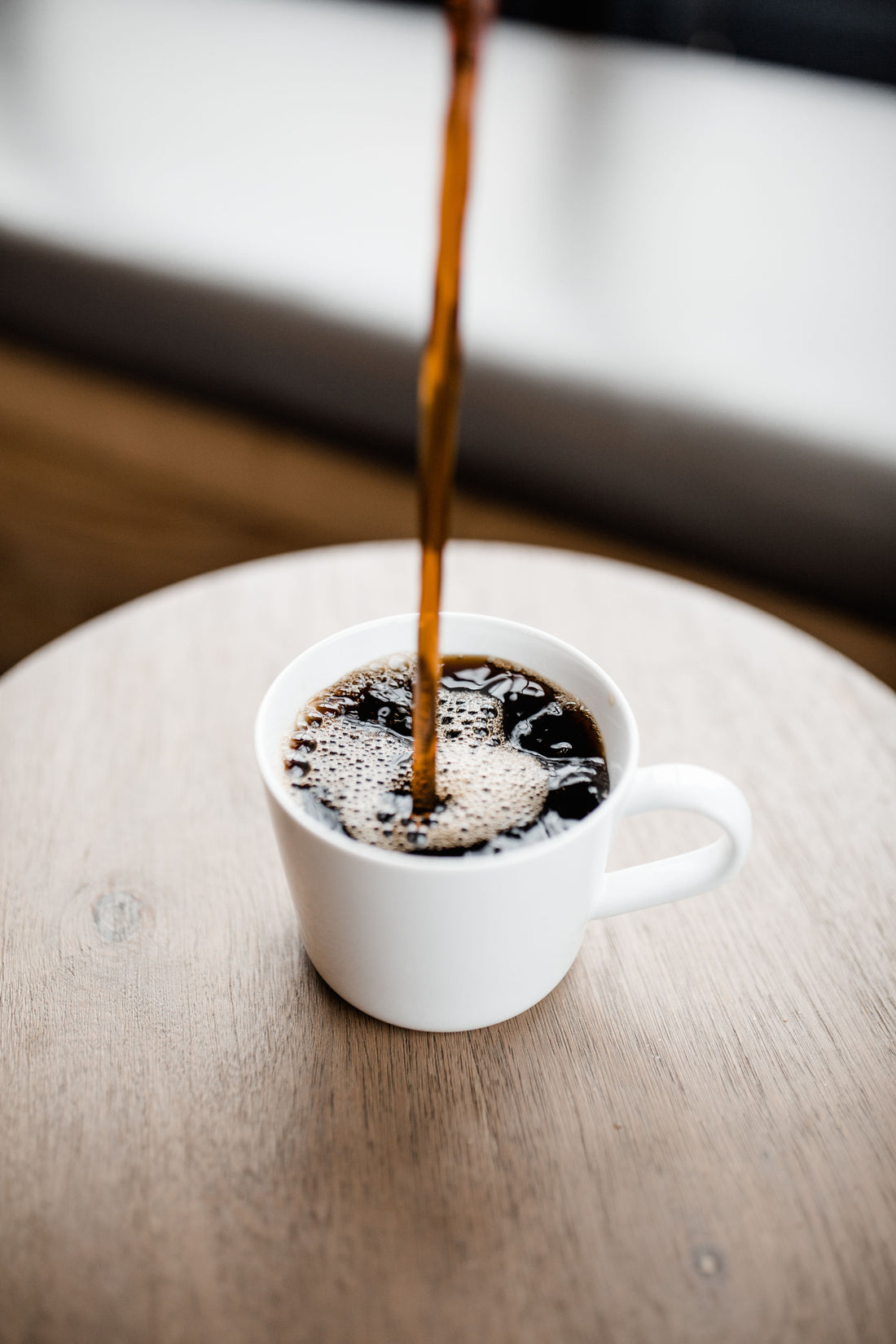 Zwarte koffie wordt in een witte mok gegoten voor een Americano