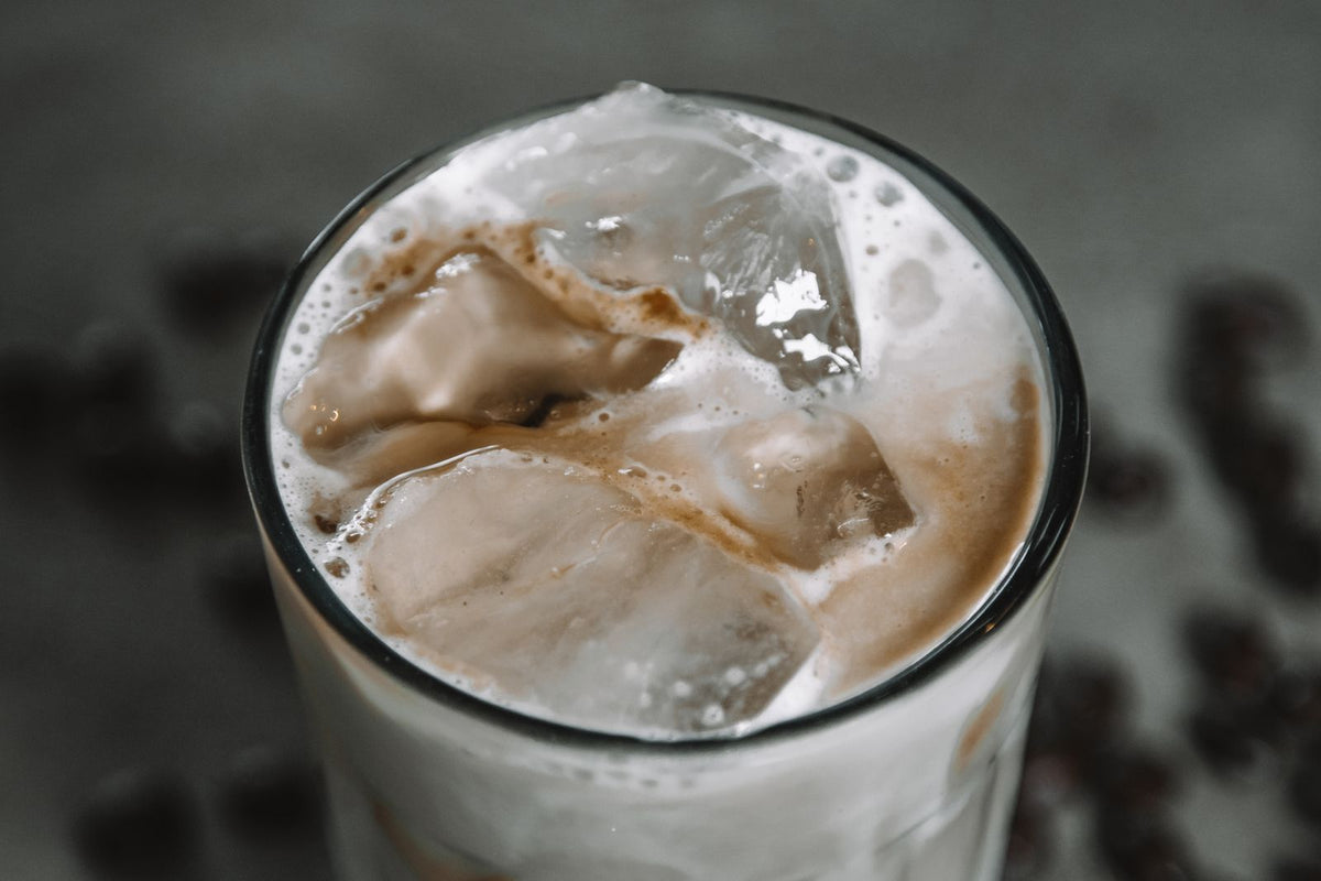 Een glas ijskoffie met schuim en ijsblokjes, gemaakt van geschudde espresso