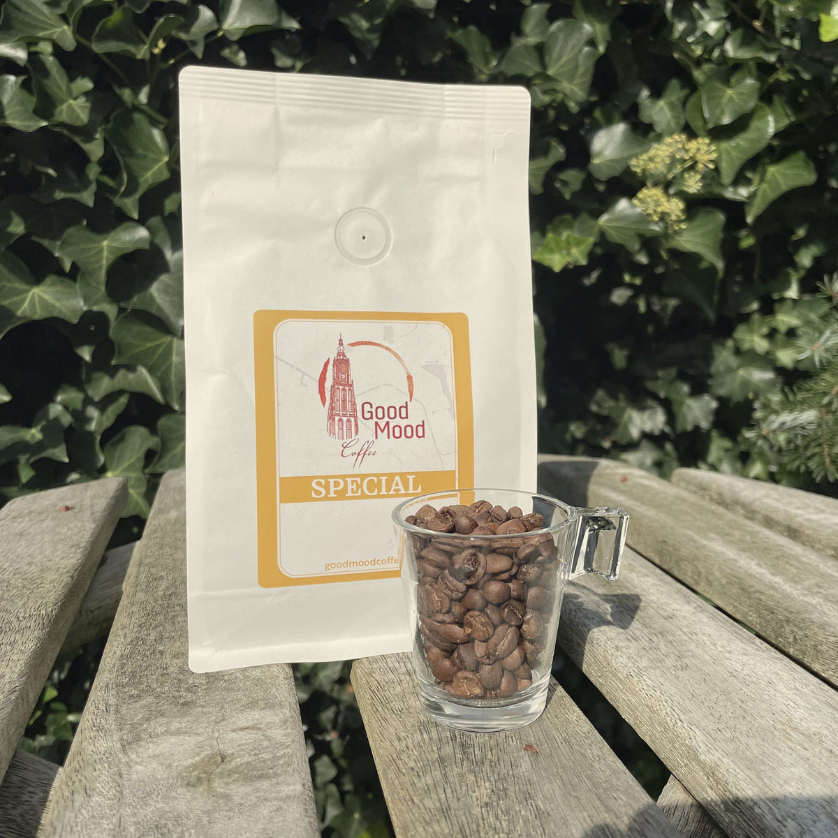 Zak Wisselende Special van Good Mood Coffee met een glas vol versgebrande koffiebonen