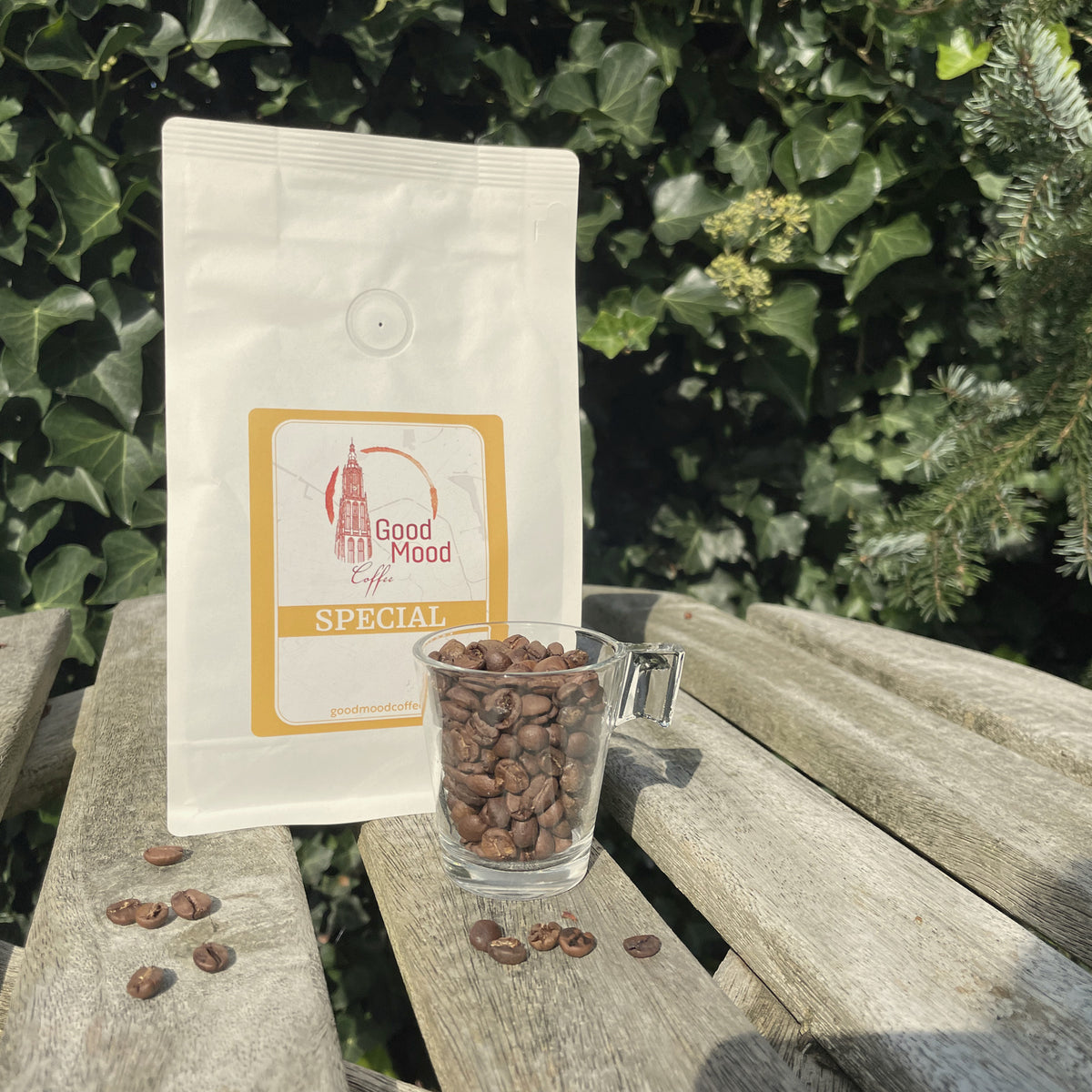 Glas koffiebonen voor de zak Wisselende Special van Good Mood Coffee, met losse bonen op de houten tafel
